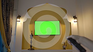Wall with TV and green screen in the style of the Middle East and North Africa. Hand with remote control. Arab Cup in