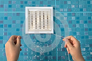 Wall ventilation grille, air flow regulator with cord and hands.