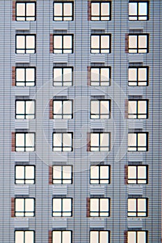 Wall of a white building with luminous windows, background. Closeup of the facade of the house with balconies