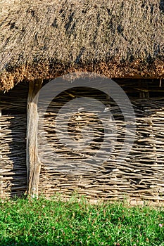 A wall of wicker twigs and a roof of reeds. Old rural building.