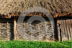 A wall of wicker twigs and a roof of reeds. Old rural building.