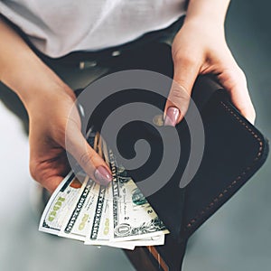 Wallet with dollar bills in female hands