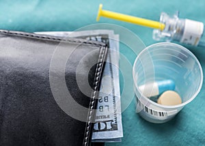 Wallet with dollar next to medicines