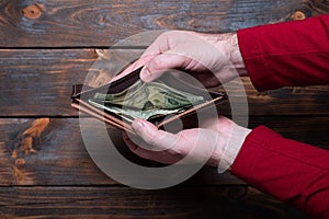 Wallet with dollars in men`s hands. Wallet with money on a wooden background