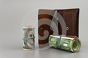 wallet with dollars and rolls of banknotes on a gray background