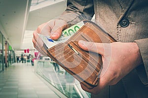 Wallet with euro money in male hands in shopping centre