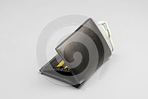 Wallet with a hundred dollar bill and credit cards on a gray background