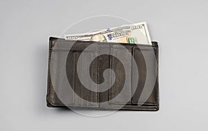 Wallet with a hundred-dollar bill on a gray background