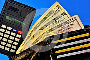 Wallet with money of different banknotes, calculator for settlements and Bank cards, on a blue background of a personal office