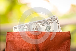 Wallet with US dollars on wood table , Money with leather orange wallet