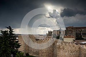 The walls of Avila and the clouds of the storm in the background and the reflection of the sun in them