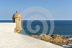 Walls and guardhouse of old fortification with the sea and stones in the background