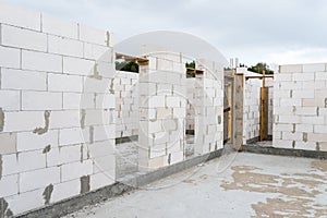 The walls of a house built of white brick with reinforced concrete pillars at the end of which there are ribbed rods, wooden formw