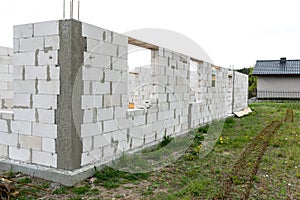 The walls of a house built of white brick with reinforced concrete pillars at the end of which there are ribbed rods, wooden formw