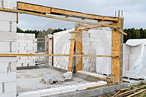 The walls of a house built of white brick with reinforced concrete pillars at the end of which there are ribbed rods, wooden formw