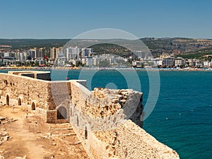 Walls of Maiden`s castle or Kizkalesi or Deniz kalesi and view of sea and Kizkalesi town, Mersin province, Turkey