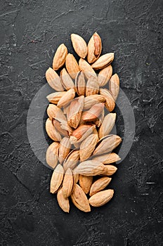 Walnut almonds in the shell. Nuts on a black stone background. Top view.