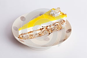 Walnut cake with yellow icing layer piece on a plate polka dots Provence isolated white background