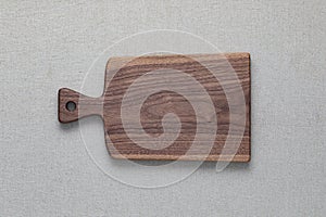 Walnut handmade wooden cutting board on burlap background.