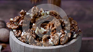 Walnut kernel macro shot. Falling walnuts, wooden bowl, dark moody background