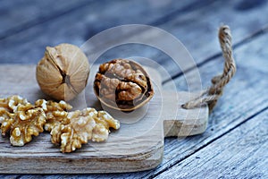 Walnut nut on wooden cutting board on wood table with green leaf background, copy space