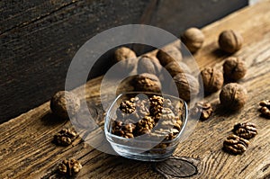 Walnut in a smale plate with scattered shelled nuts and whole nut which standing on a wooden vintage table. Walnuts is a