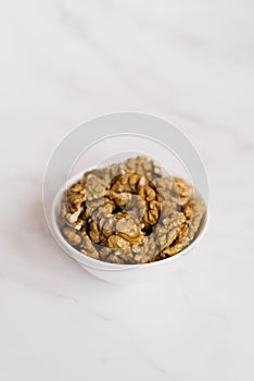 Walnut in a white bowl on a marble table