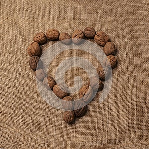 Walnuts arranged to form a heart. Rustic background of raw yuta canvas - delicious food