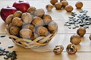 Walnuts in a basket, apples and pumpkin seeds on a tree background