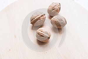 Walnuts on brown wooden plate closeup.