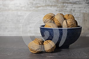 Walnuts close-up on a gray wooden background in a blue plate. Vitamin-rich nuts on the table.