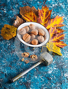 Walnuts in an enamel bowl, broken walnuts, kitchen hammer