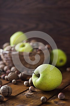 Walnuts with green apples mixed with a wicker basket