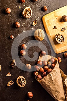 Walnuts and hazelnuts are on the table. Whole and broken nutshells lie on a brown background