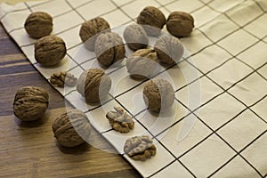 Walnuts and kernels of walnut on the rustic wooden table covered with kitchen towel. Front view.