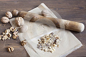 Walnuts in paper and wood battledore on a wooden background photo