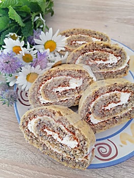 Walnuts roulade slices on a plate with beautiful daisies close up