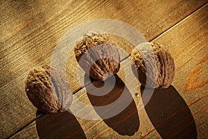 Walnuts on a rustic old wooden table. Three walnuts on a wooden table. Side view.