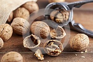 Walnuts in shell with nut cracker on wooden background