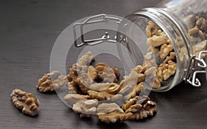 Walnuts. Walnut kernels are poured out of a glass jar, which lies on a dark table