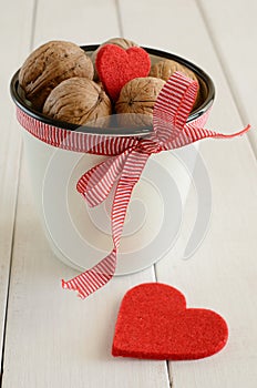 Walnuts in white cup and two red hearts