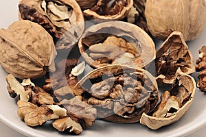 Walnuts on white plate, Walnuts kernels and shells background