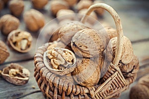 Walnuts in wicker basket on old wooden rustic table. Selective f