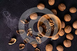 Walnuts in wooden bowl and on black slate surface. Healthy nuts and seeds composition.