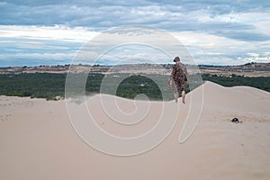 Wanderer walking in the desert. Young man standing in white sand dunes.