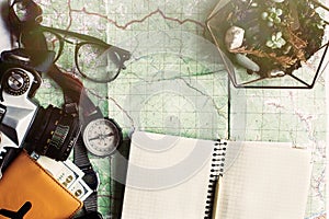 wanderlust and adventure concept, compass camera glasses passport money notebook and succulents lying on map, top view, space for