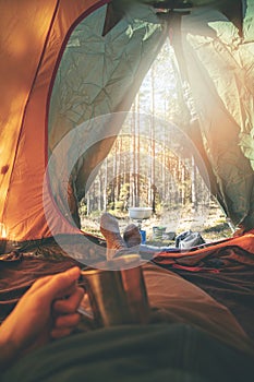 Wanderlust - man relaxing in tent after hike with cup of tea