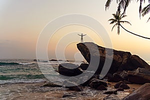 Young man on a rock in a tropical location. Getting away from it all photo