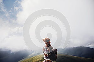 A viajar. viajero en un sombrero mochila mira a nubes en montanas. elegante lumbar una mujer para el conocimiento 