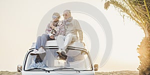Wanderlust and travel destination happiness concept with old senior beautiful couple sitting and enjoying the outdoor freedom on